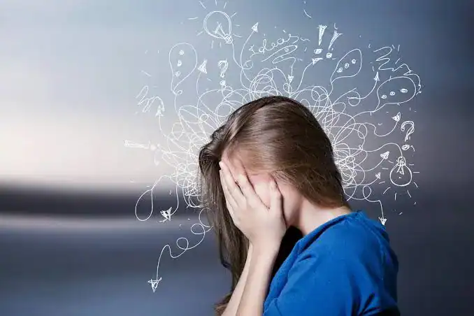 Young woman with hands covering face, surrounded by doodles of ideas and questions.