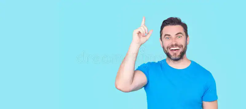 Happy man pointing up against a blue background for positive mindset.