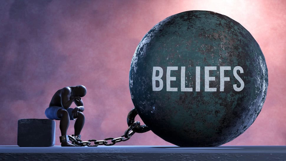 Person sitting with head down next to a large ball labeled 'BELIEFS'.